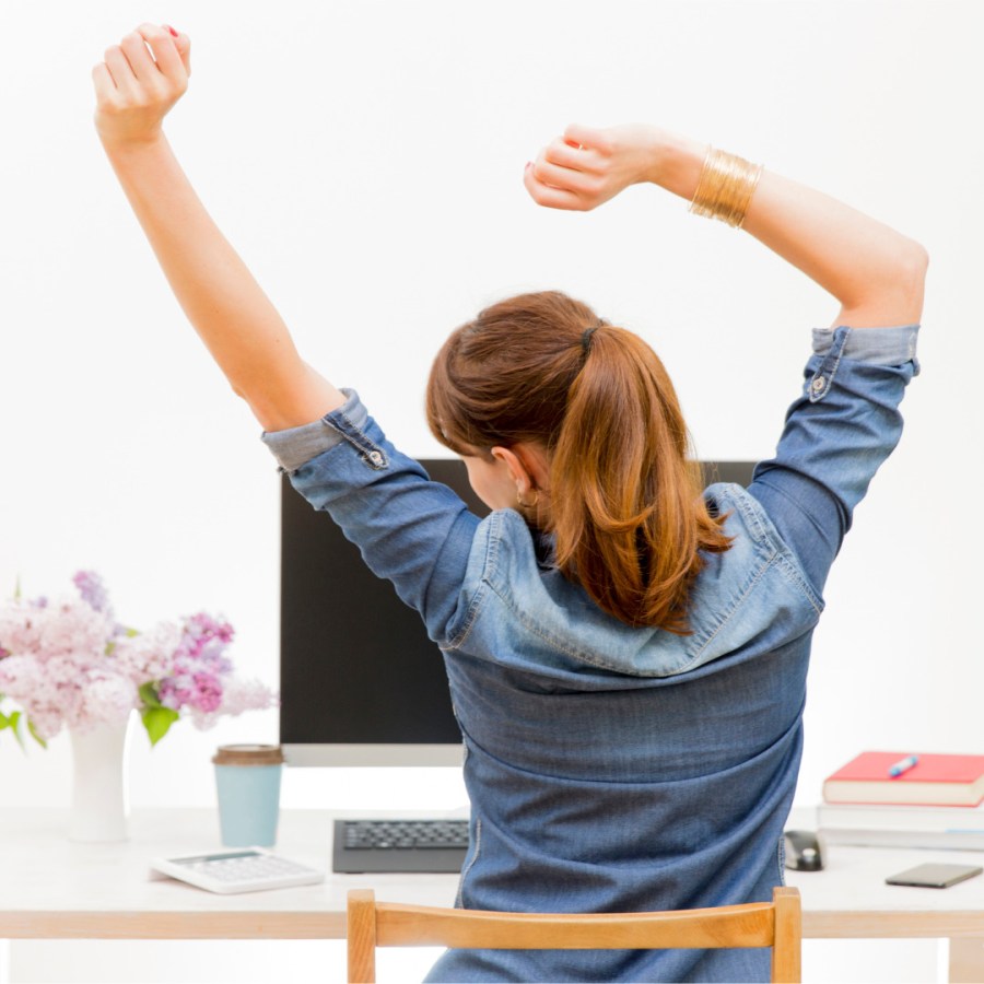 woman-stretching-her-arms-sitting-by-the-table-at-work-next-to-picture-id693430128